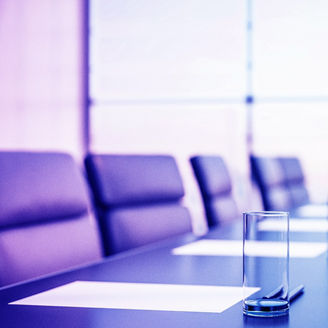 Close up of conference room with glasses of water on the table with papers, armchairs and a large window. 