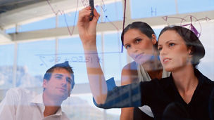 Businesswoman drawing graphs on glass