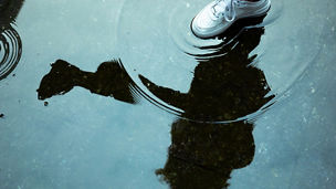 Japanese alt text: 水たまりを踏む白いスニーカー