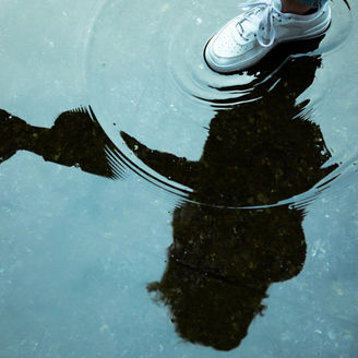  水たまりを踏む白いスニーカー