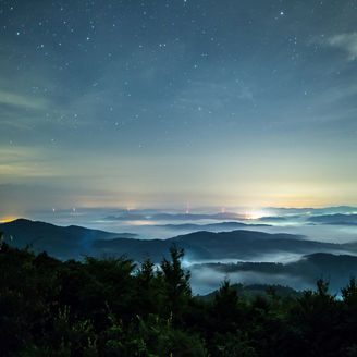 星空と雲がかかる夜の山