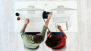 High angle shot of a young man helping his colleague in a call centre