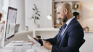 Computer, documents and businessman on digital tablet for planning, finance or budget in coworking space. Financial advisor, online and male check savings, growth or review, serious and focus mindset