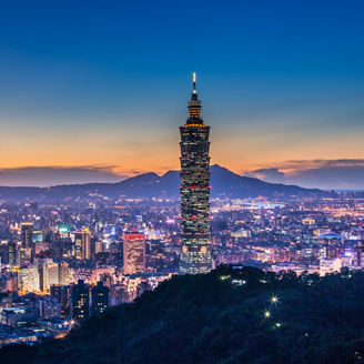 High angle shot of Taipei 101 at night with sunset afterglow in the back and city lights.