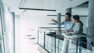 Shot of two colleagues having a discussion in modern office. Confident business people working together in the office. Creative business persons discussing new project and sharing ideas in the workplace.