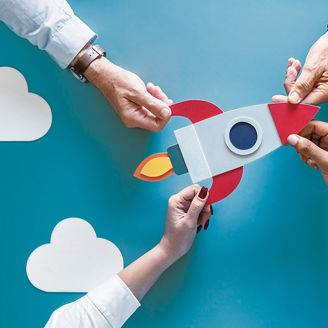 ロケットのイラストの4隅をつかむ人の手