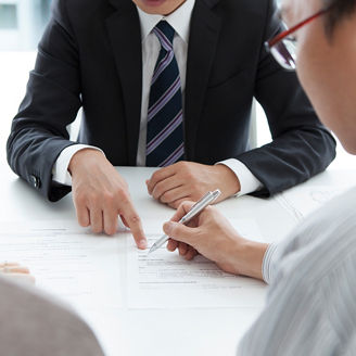 資料を指さす2人の男性と眺める女性