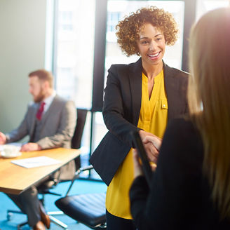 Japanese alt text: 握手する女性とミーティング中の男性