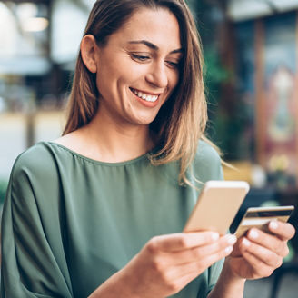 Young woman shopping online in cafe using smartphone and credit card