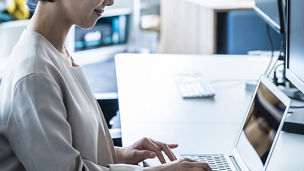 Japanese businesswoman typing on laptop in bright modern office with calm blue tones