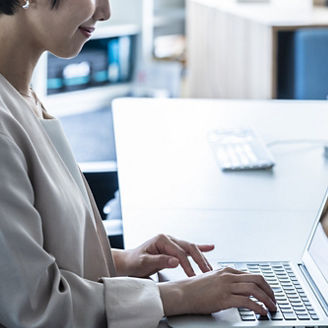 Japanese businesswoman typing on laptop in bright modern office with calm blue tones