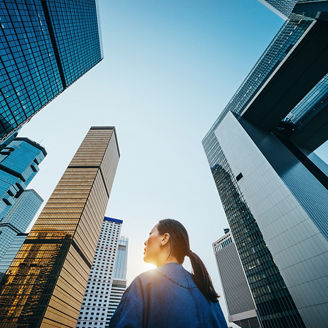 オフィスビル群の谷間をゆく一人の女性