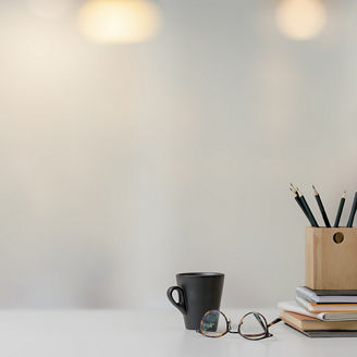  眼鏡とカップと鉛筆のあるデスク