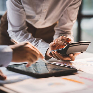 Young colleagues discuss business and analytical price charts using calculators and laptops to calculate financial, tax, accounting, statistics and analytical research ideas.