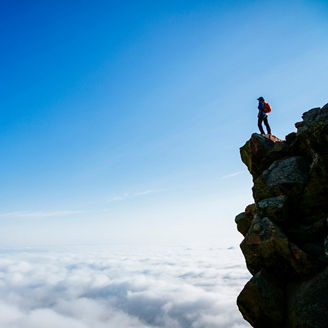 A woman atop the second Flatiron as cloud covers the city of Boulder below, Colorado, USA