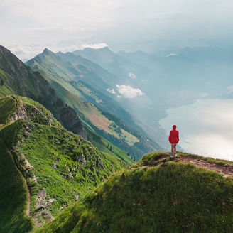 Aerial view of woman in red coat standing on top of the mountain ridge Augstmatthorn