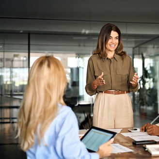 Happy middle aged business woman executive ceo leader discussing project management planning strategy working with diverse colleagues company team at office corporate board group meeting.