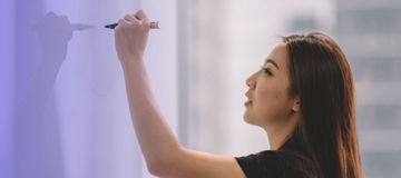 Frau schreibt auf Whiteboard