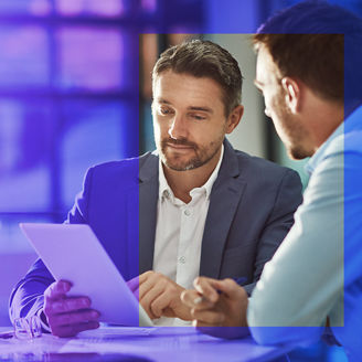Two men in conversation looking at a tablet