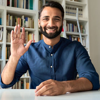 Smiling indian professional business man teacher coach waving hand looking at webcam remote working by video call, hybrid office online meeting, leading webinar training or learning class, screen.