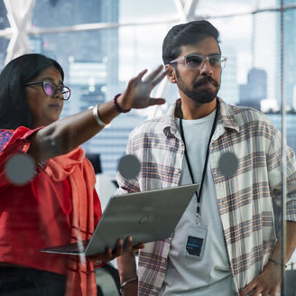 Female and Male Indian Financial Advisers Use Laptop Computer to Discuss a Stock Market Strategy in a Modern Company. South Asian Managers Collaborate on a Banking Research and Development Project