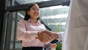 Medical sales representative greeting a doctor with a handshake at the hospital - healthcare and medicine concepts