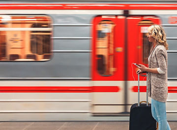 Lady holding suitcase standing outside moving train