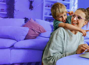 Lady working on laptop with child hugging her