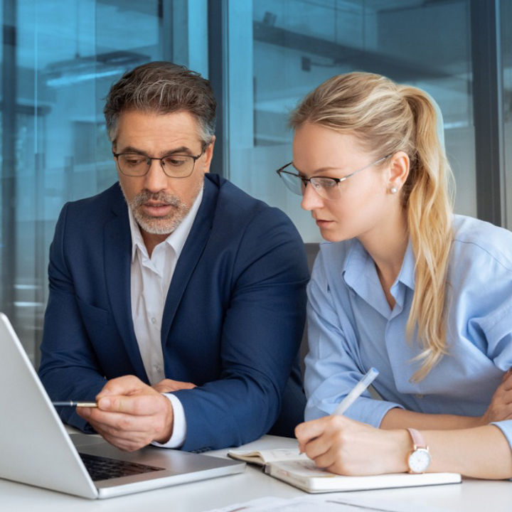 Two people sat at a table looking at a laptop
