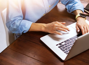 Young beautiful woman working with a laptop. Female freelancer connecting to internet via computer. Blogger or journalist writing new article.