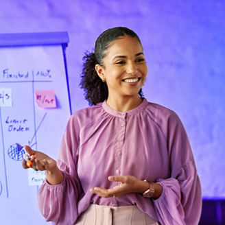 Mulher a apresentar uma ideia enquanto atrás é visível um quadro com dados escritos