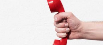 Mano sosteniendo un teléfono rojo