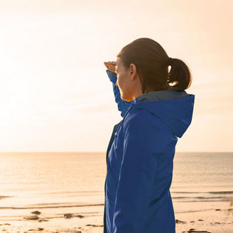 Woman on beach looking towards sun