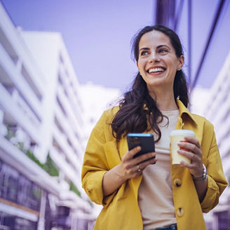 Vrouw loopt met koffie en haar telefoon in haar handen