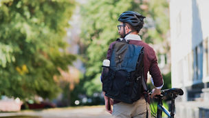 Male commuter or messenger with a bike in urban background. Safe cycling in the city, going to work by bicycle, delivery man image