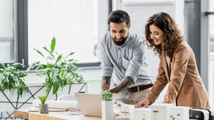 smiling virtual reality architects looking at laptop in office