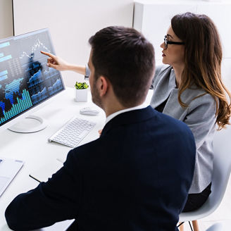 Homem e mulher a visualizar dados em dois computadores