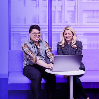 Man and woman sitting and smiling looking at the laptop