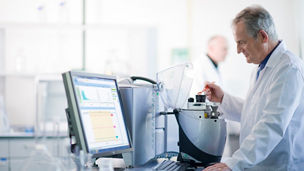 Man in a white coat working on a machine and computer