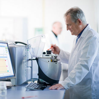 Man in a white coat working on a machine and computer