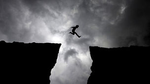 Man jumping from cliff - Dark clouds