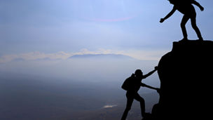 Man lending helping hand to woman hiker