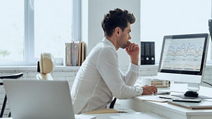 Man looking at statistical graphs on computer screen
