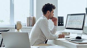 Man looking at statistical graphs on computer screen
