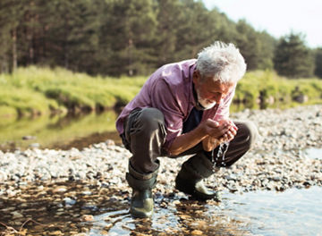 man drinking water from river