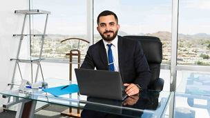 Portrait of a good-looking business executive and businessman feeling happy and doing a lucrative job at his stylish office with a big city view