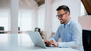 man smiling and working on laptop