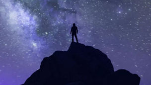 Man standing on top of mountain looking at the galaxy