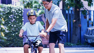 Man teaching son to ride bicycle banner