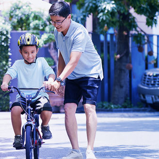 Man teaching son to ride bicycle banner